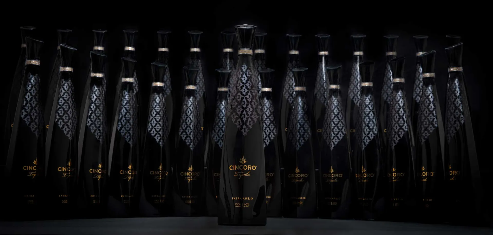 Cincoro Tequila evergreen hero bottle in front of rows of matching bottles on black, packshot photography