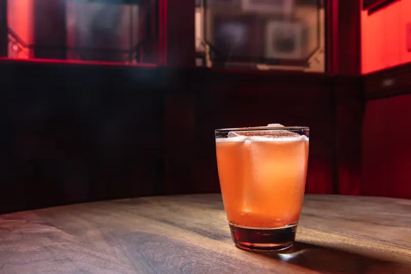 Doctor's Orders cocktail from The Dead Rabbit, lit on a dark bar.