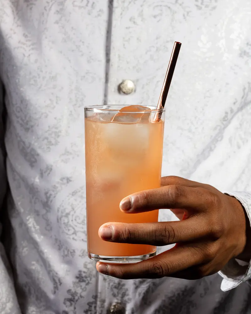 Hand holding a greyhound cocktail in a highball, HH Bespoke Spirits.