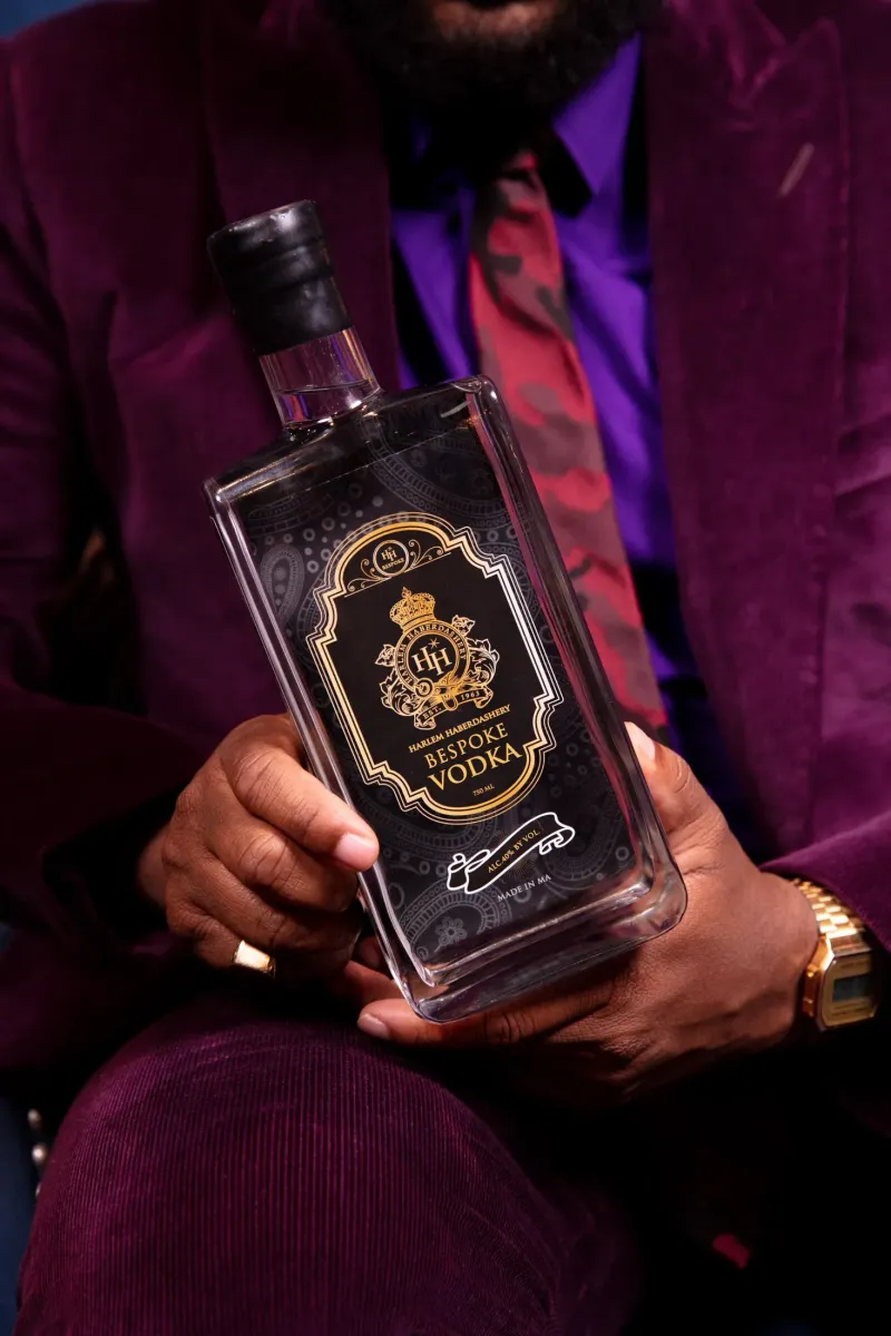 HH Bespoke vodka bottle held across the lap of a man in a purple velvet suit