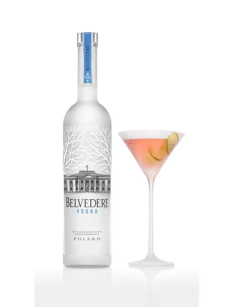 Belvedere vodka bottle beside a pink martini in a frosted stemmed glass with a lime wheel, photographed on white.