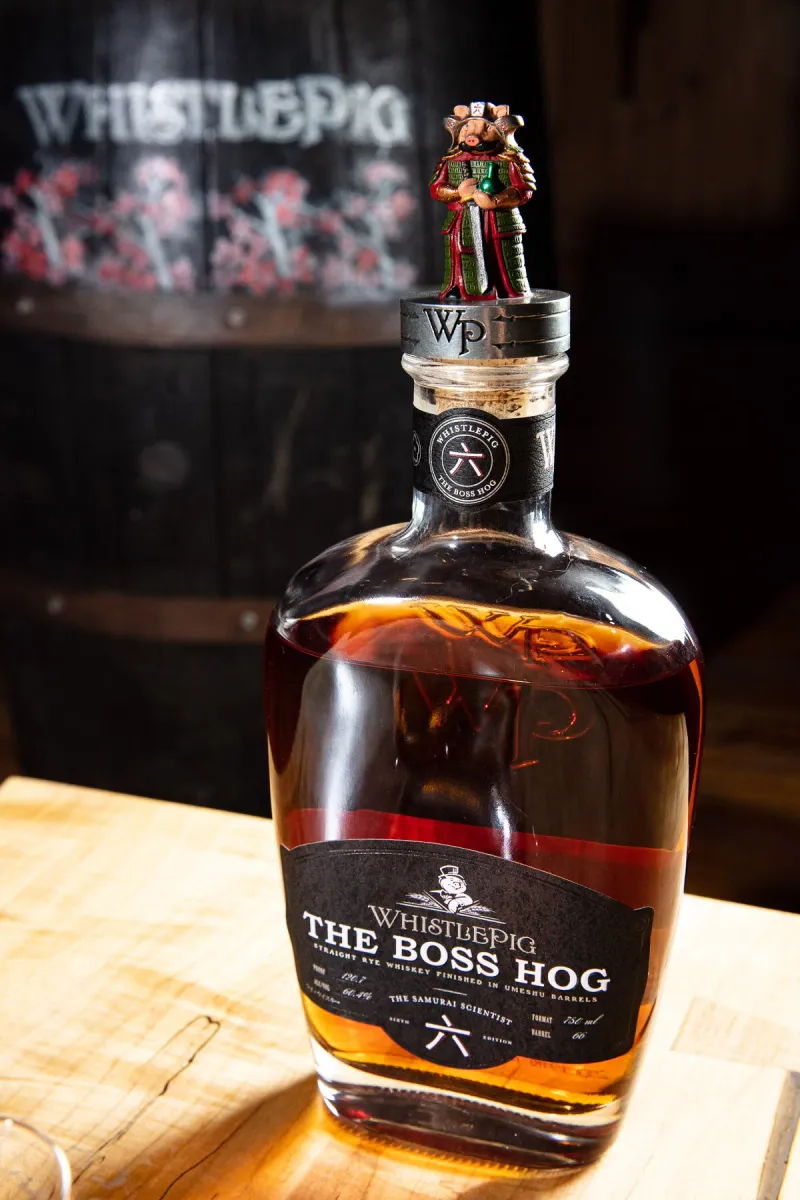 WhistlePig Boss Hog bottle on a whiskey barrel with the WhistlePig branded barrel head behind